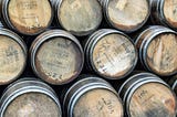 Stacks of whiskey barrels with their batch info and year stamps imprinted on their faces