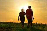 Two people walking at sunset