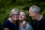 Family embracing a man with down syndrome and smiling to each other.