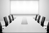 board room with a long white table and black leather chairs