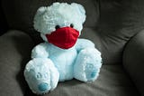 stuffed blue teddy bear wearing a red mask