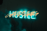 Orange scribble over the word “Hustle” in neon lights