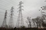 Power lines tower over a dark landscape