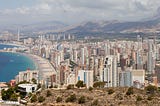 A view of the city of Benidorm, Spain, highlighting the contrast between its high-rise architecture and the surrounding countryside