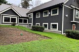 A large two-story building that is gray with white trim.