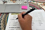 Computer keyboard and printed sheets from a textbook in Portuguese