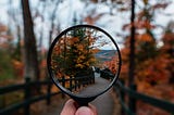 Hand holding magnifying glass. Looking down path. In the magnifying glass crystal clear image of the path. Outside blurry.