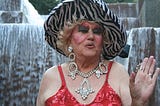 Drag queen Darcelle XV in red dress, costume jewels, and zebra striped hat at Portland’s Keller Fountain, circa 2012