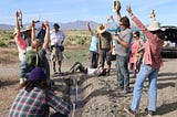 The Ripple team celebrates with their arms up in the air as the irrigation water makes its way to the final newly-planted willow tree. Shouting and hats in the air!
