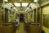 the inside of a subway train lined with empty seats