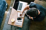 man in black shirt writing in front of computer on sofa, best month on medium