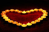 Tealight candles arranged around a red heart shape