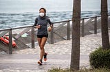 A young woman with a face mask jogs along the waterfront in Hong Kong,