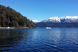 an image of the port in Villa La Angostura, with a view of the lake, the forest and the mountains with snow