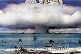 A “mushroom cloud” rises from the sea through a condensation cloud off Bikini Atoll in a colorized photo from 25 July 1945