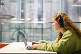 A students sits in the Laidlaw Library and works on their laptop whilst lisitening to music through headphones.