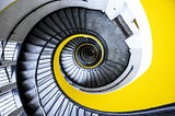 Looking down a spiral staircase with a yellow background.