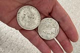 Two old silver dollars in my hand