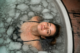 a woman in a bathtub filled with ice-cold water; chunks of ice floating around her