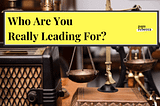 Antique scales on desk with yellow banner with text “Who are you really leading for?”