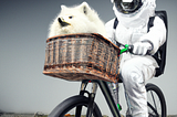 Astronaut on biccyle with fluffy Pomeranian in the basket