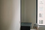 Quiet room with a simple desk and empty chair beside a window, filled with soft natural light, suggesting reflection, attention, and a slower pace of thinking