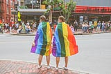 Two women wear rainbow flags on Congress Street in Portland, Maine during the annual Pride parade