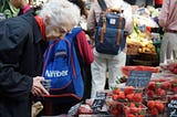 Elderly lady carefully selecting fresh fruits in the grocery store’s produce section