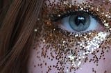 Closeup of woman’s eye with glitter on her face.