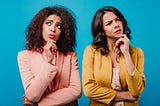 Front view of pensive girls. African woman and latin lady posing on blue background.