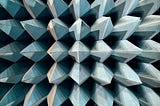 Large spiky 3-D metal points lined up next to each other and facing towards the viewer. It appears to be abstract shapes but is an image of the walls of an anechoic chamber.