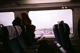 A woman sits alone on a train, reading a book.