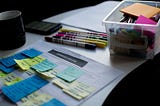 Sticky notes on paper document beside pens and box