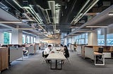 man and woman sit at a table in an open, modern office