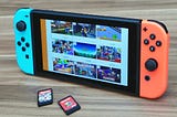 A Nintendo Switch turned on to feature an assortment of games, including two cartridges.