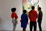 People studying a large painting of a stag at a gallery