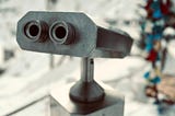 A close-up of a pair of metal, mounted binoculars, which superficially resembles a robot’s face.