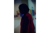 A picture of the Author, Keyukemi at art exhibition. The picture has been edited to highlight her red jacket amidst the darkness around