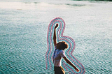 fotografia de uma pessoa pulando com um rio ao fundo. todo o contorno da pessoa está bordado com linhas coloridas