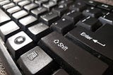 A close-up of a modern computer keyboard with the “shift” key in the foreground.