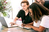 Man Working on Laptop while Woman Takes Notes