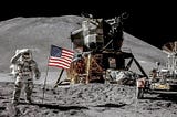 An astronaut stands on the moon with the american flag rooted on the ground. A remastered photo of the Apollo 15 mission which land the first men on the moon.