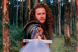 Knight with long hair holding his sword directly at the camera.