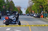A Police motorcycle parked beyond a yellow warning tape in the middle of a street.