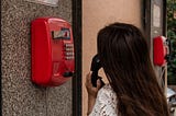 Woman making a phone call with a red payphone