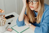 Woman sitting at desk holding a laptop looking disappointed.