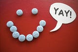 Birth control pills arranged in a smiley face with a speech bubble saying “yay!”