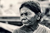 black and white photo of older brown-skin woman’s face as she looks towards the left with a slight frown