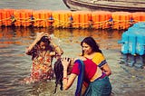Three middle-aged ladies are bathing in the Gange river near Allahabad, India. They are dressed with colorful saris.