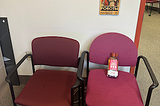 Two chairs in my office. One has a bottle of “Tres Comas” tequilla on it.